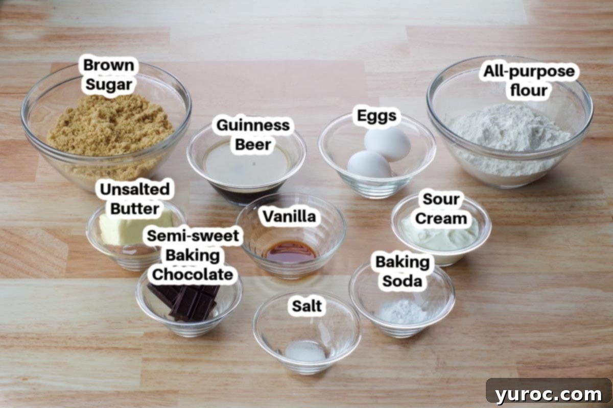 Various baking ingredients for chocolate Guinness cake, including semi-sweet chocolate, butter, Guinness beer, and sour cream, arranged in glass bowls and labeled.