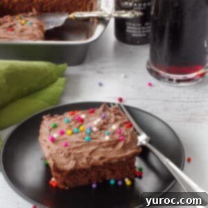A piece of chocolate Guinness cake with Irish cream frosting on a black plate.
