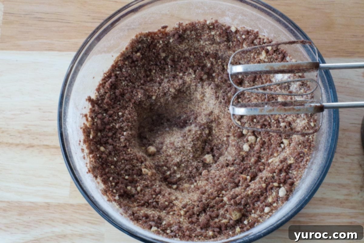 Melted chocolate and butter mixture being added to the dry ingredients in a glass bowl.