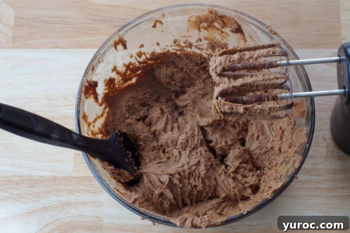 Guinness beer being poured into the cake batter mixture in a glass bowl.