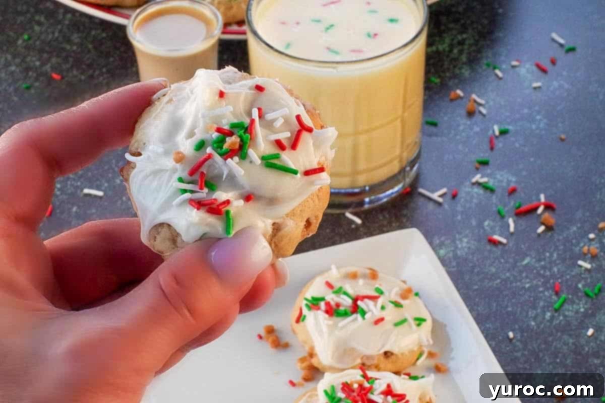 an eggnog and baileys irish cream cookie being held up over a white plate with more cookies