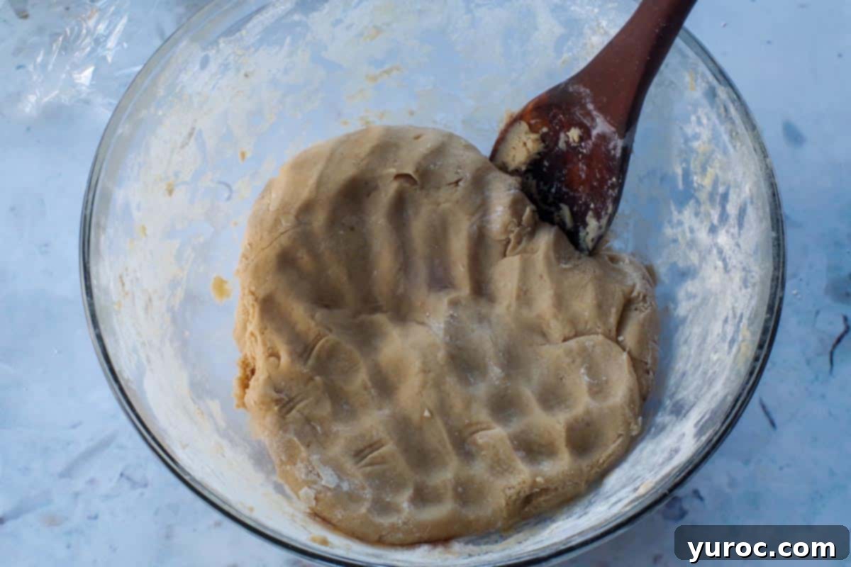 cookie dough in glass bowl with wooden spoon