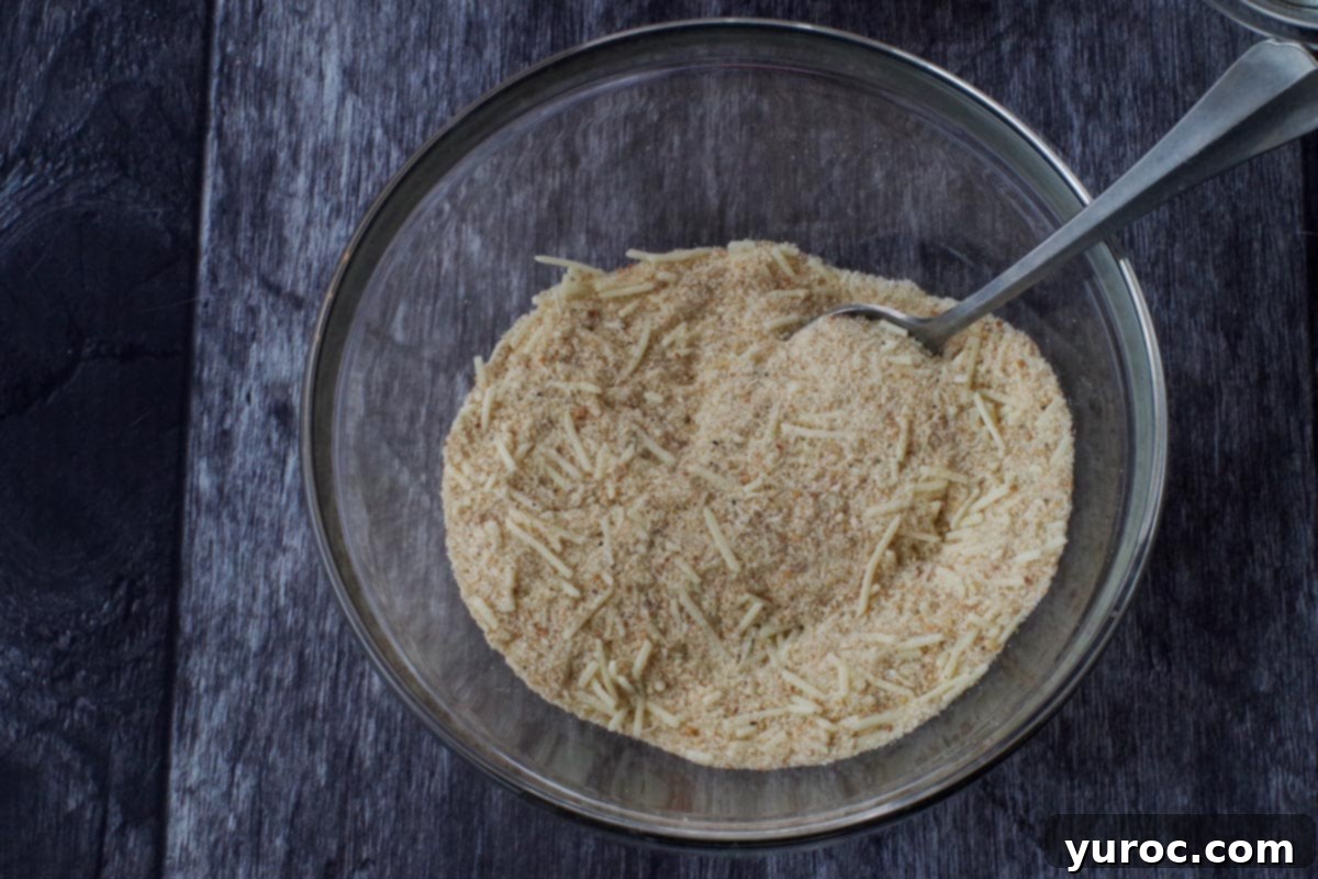 Bread crumb mixture in a glass bowl with a metal whisk, ready for coating.