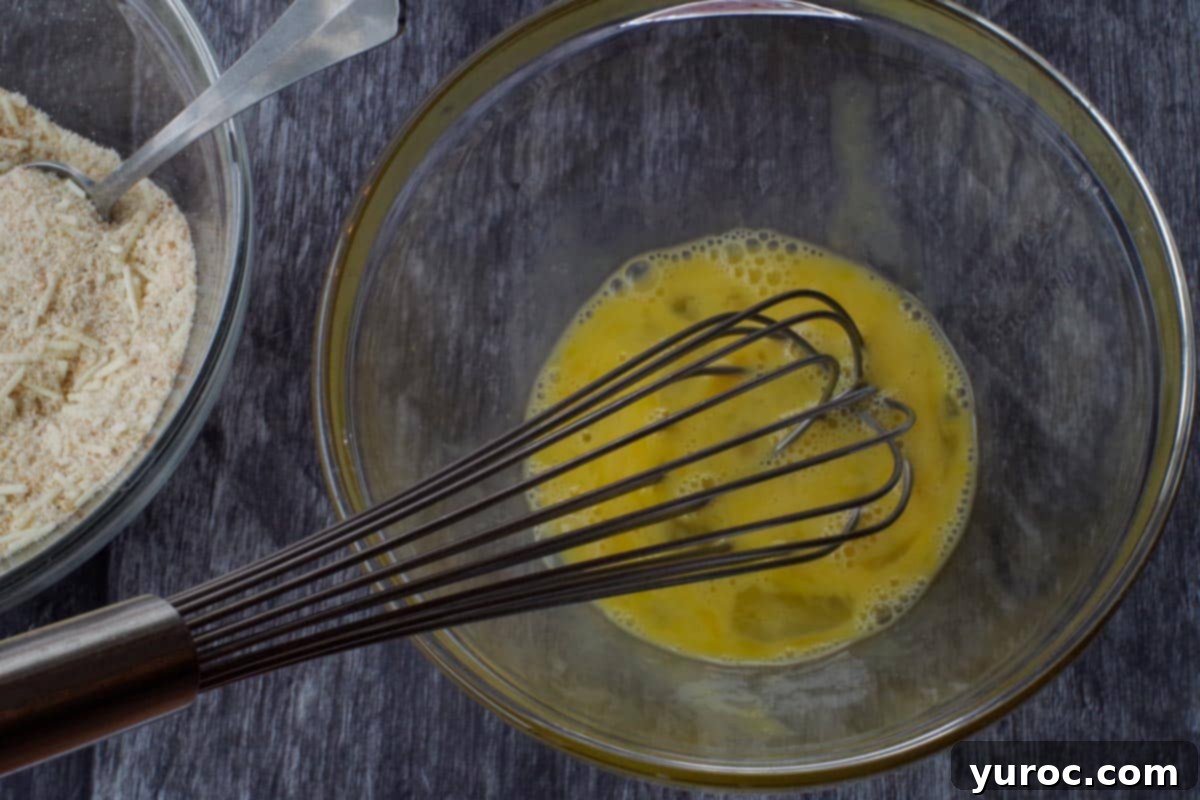 Two whisked eggs in a glass bowl, prepared for dipping.