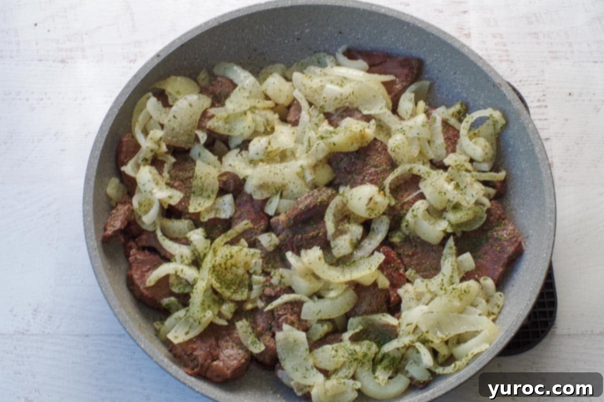 onions added to skillet with venison, beginning to soften and brown