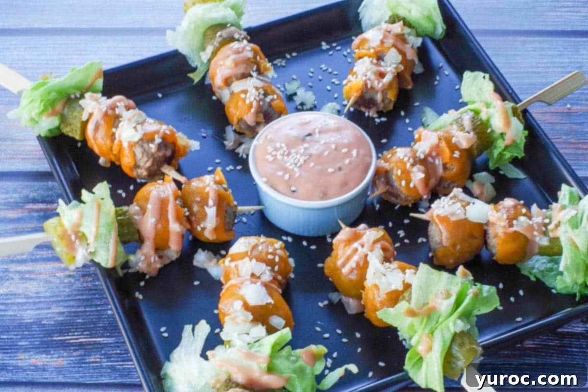 Big Mac Bites arranged on a sleek black serving platter, with a small bowl of Big Mac special sauce in the center for dipping, garnished with fresh lettuce and sesame seeds.
