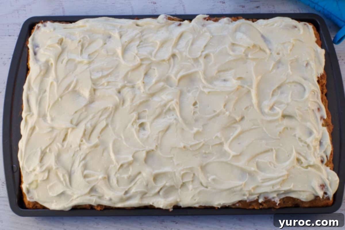 The baked sheet pan carrot cake pancakes are generously frosted with a smooth layer of sweet cream cheese butter, resembling a beautifully frosted cake.