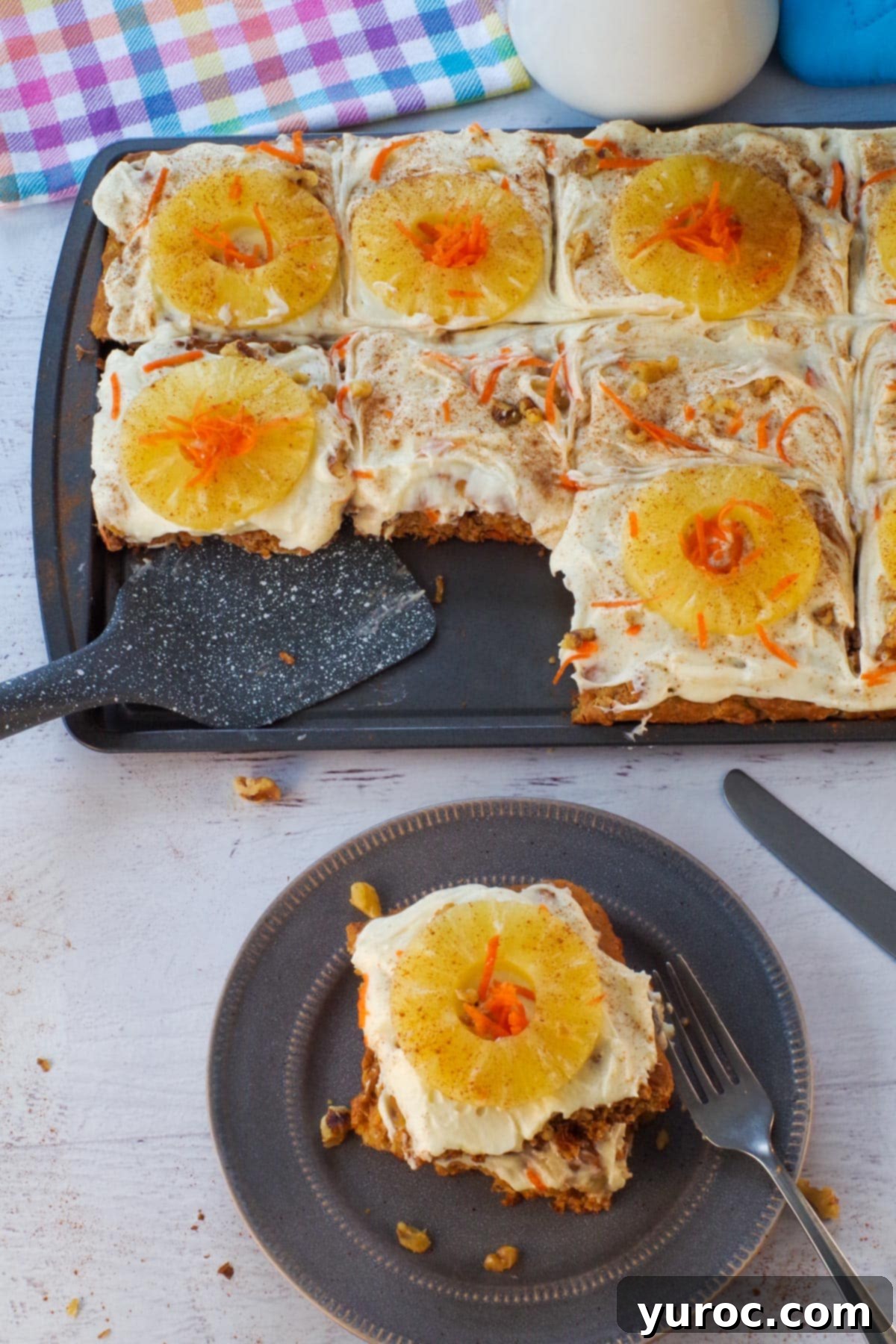Two enticing sheet pan carrot cake pancakes resting on a sleek grey plate, with the baking sheet full of additional pancakes blurred in the background, inviting you to indulge in this breakfast treat.