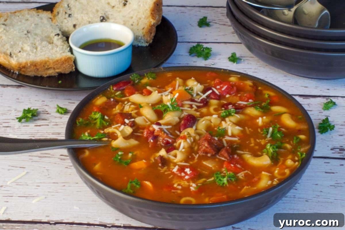 Hearty Ham and Macaroni Soup 2 A steaming black bowl of leftover ham macaroni soup, with more elegant black bowls in the soft-focus background, accompanied by slices of savory onion and olive bread ready for dipping in olive oil and balsamic vinegar.