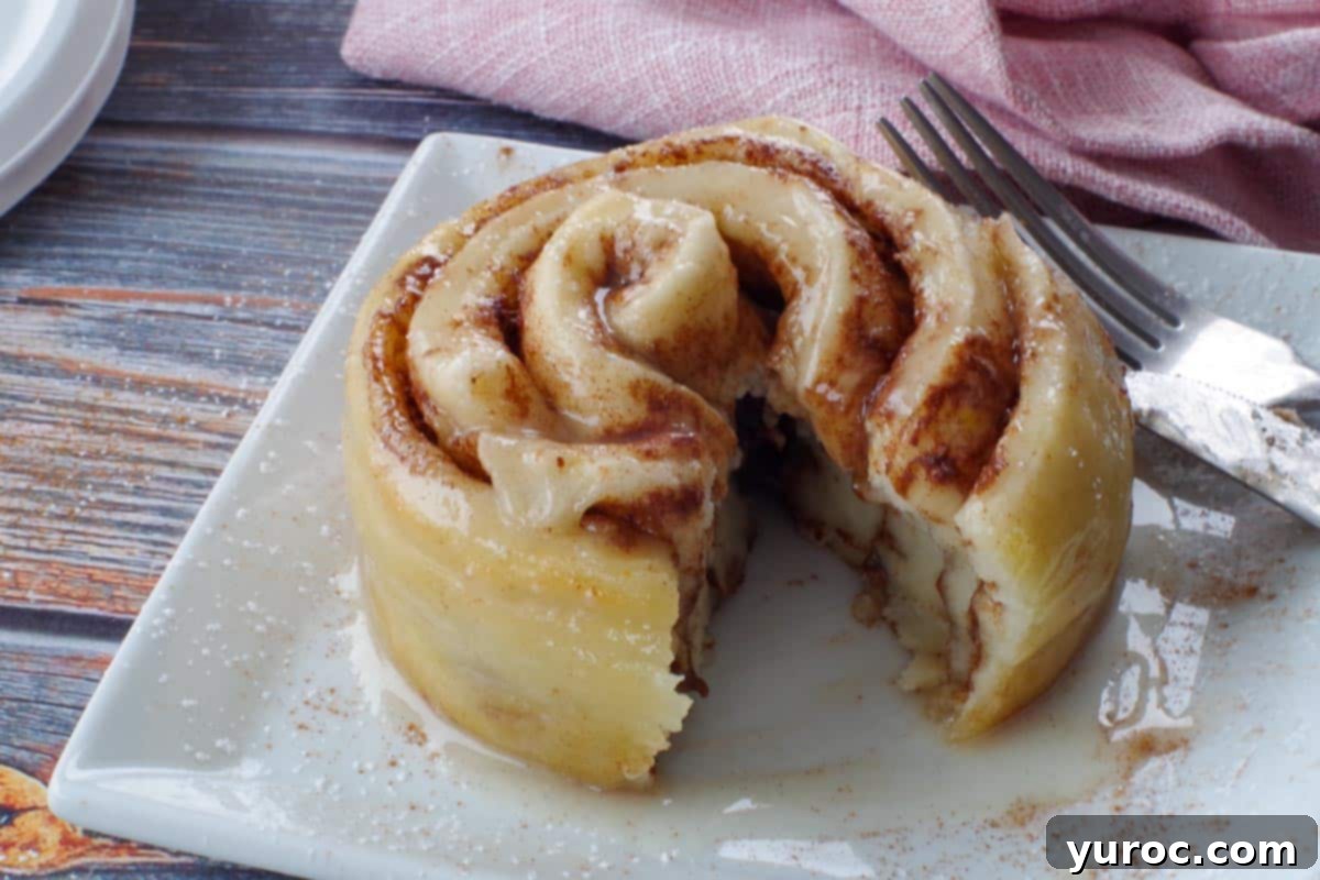 healthy cinnamon roll in a mug cut open on a white plate, with a pink napkin in the background