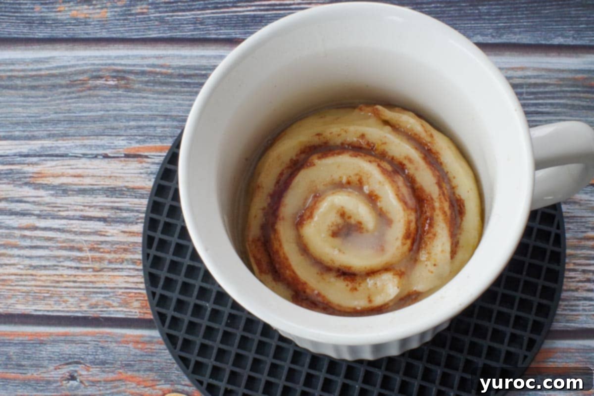 Healthy Cinnamon Swirl Mug Treat 20 cinnamon roll in a white meal mug on a black round trivet