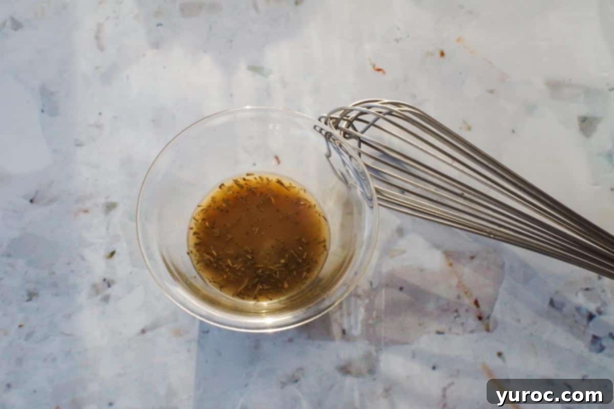 dressing ingredients whisked together in a glass bowl with whisk on the side