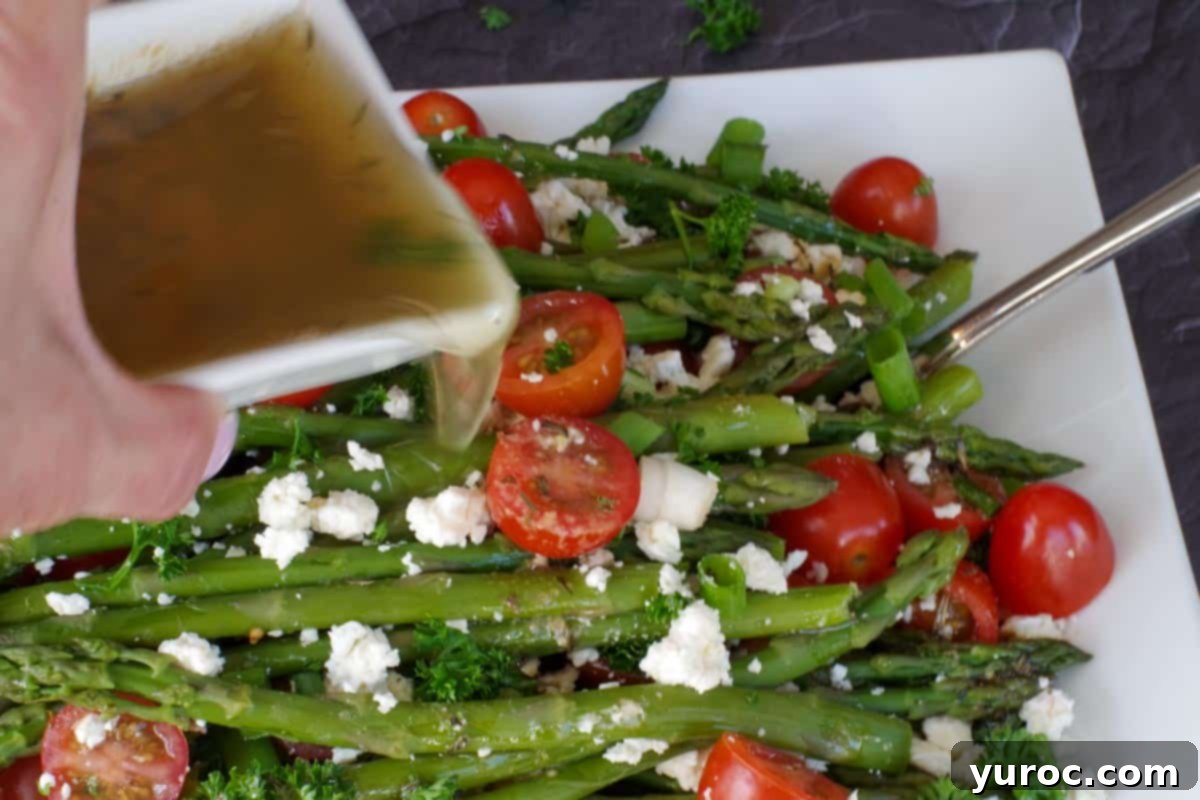 dressing being poured over asparagus salad