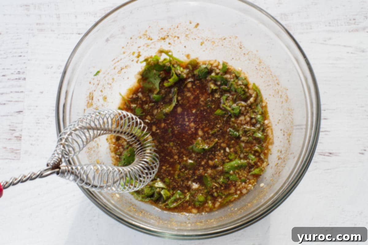 marinade ingredients in glass bowl with metal whisk