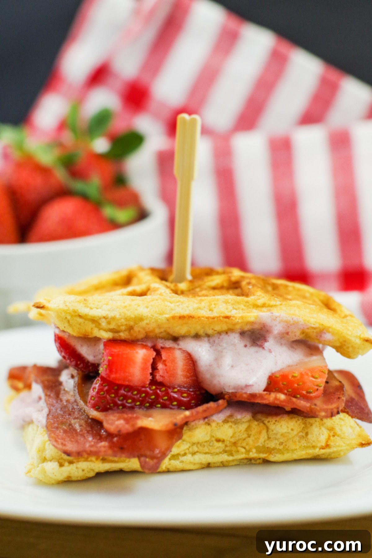 A beautifully presented healthy chicken and waffle sandwich with sliced strawberries, emphasizing its appeal as a gourmet yet wholesome meal.