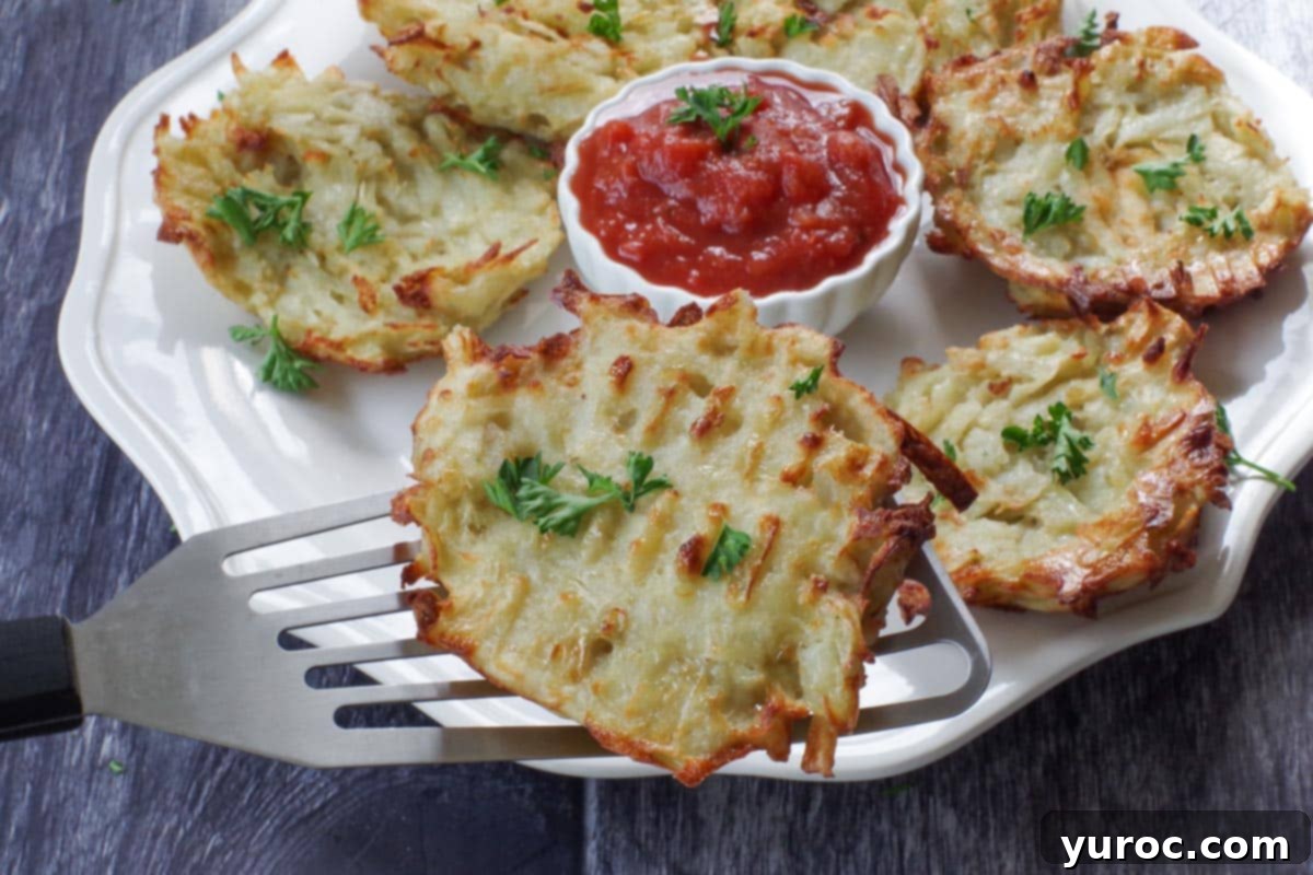 shredded air fryer potato pancake being lifted of a white plate with more potato pancakes and a white bowl of salsa in the middle