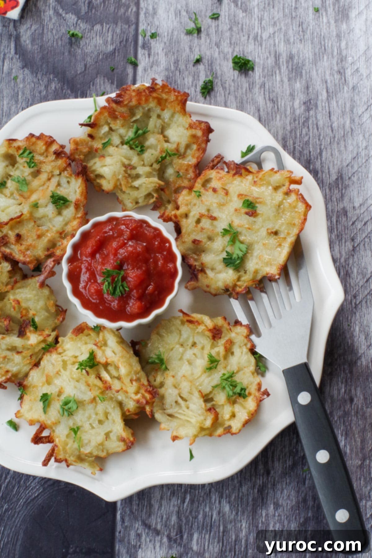shredded air fryer potato pancakes on a white plate with a white bowl of salsa in the middle
