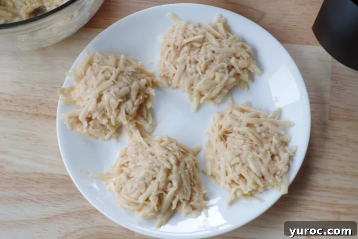 4 raw potato pancakes on white plate prior to cooking