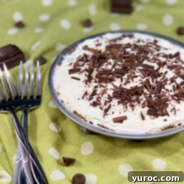 A complete chocolate cream pie elegantly displayed on a green background with white polka dots, accompanied by a pair of forks.