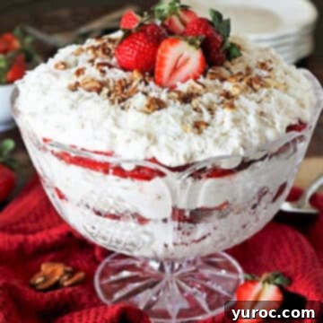 A vibrant strawberry coconut punch bowl cake elegantly displayed on a red fabric background, surrounded by fresh strawberries.