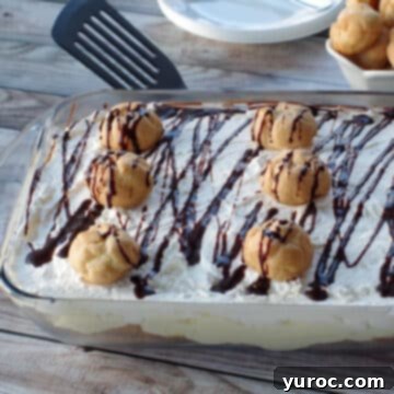 A delightful cream puff dessert showcased in a glass dish, with additional plates and a bowl of cream puffs artfully arranged in the background.