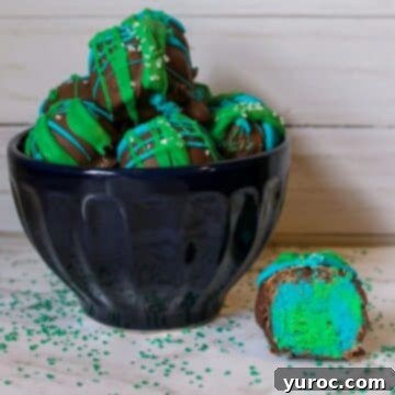 Earth Day Cake Bites in a black bowl, with one cake bite sliced open to reveal its colorful interior, displayed beside the bowl.