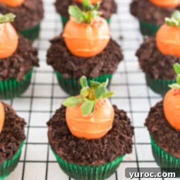 Delightful carrot patch cupcakes displayed on a wire rack, featuring chocolate cupcakes with strawberry 'carrots' in 'dirt'.