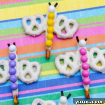 Four vibrantly colored rainbow dragonfly pretzels arranged on a multicolored background, showcasing their fun and whimsical design.