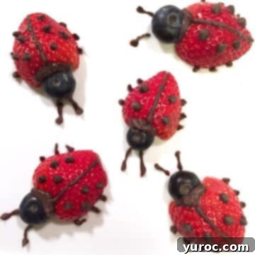 Five adorable ladybug-themed strawberries neatly arranged on a clean white background, showcasing a healthy and fun snack idea.