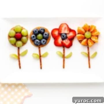 Four brightly decorated flower crackers arranged on a pristine white platter, highlighting a fun and healthy snack choice.