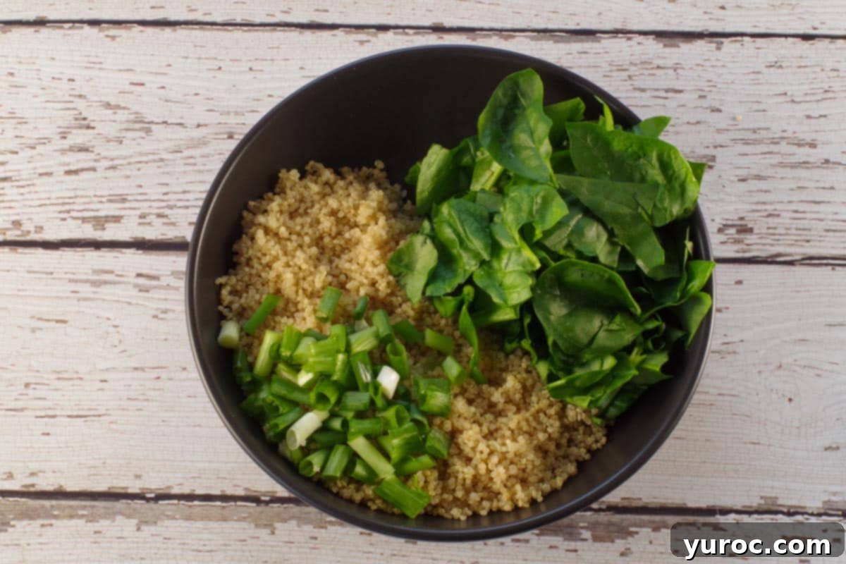 Avocado Breakfast Power Bowl 5 chopped spinach and green onion added to quinoa in black bowl