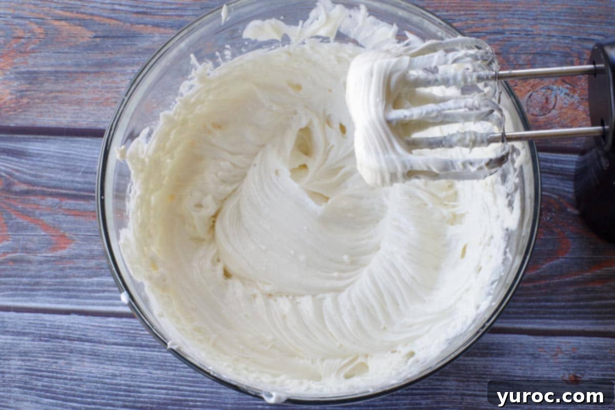 cream cheese, sugar, Greek yogurt, sour cream, coconut extract and melted white chocolate in a glass bowl, beaten together