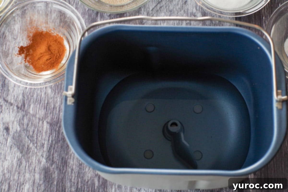 Water added to bread pan, with dry ingredients in bowls, in the backgroun