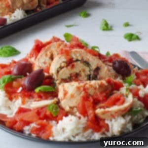 Mediterranean Slow Cooker Stuffed Chicken breast on rice, on a black plate with basil leaves in the background