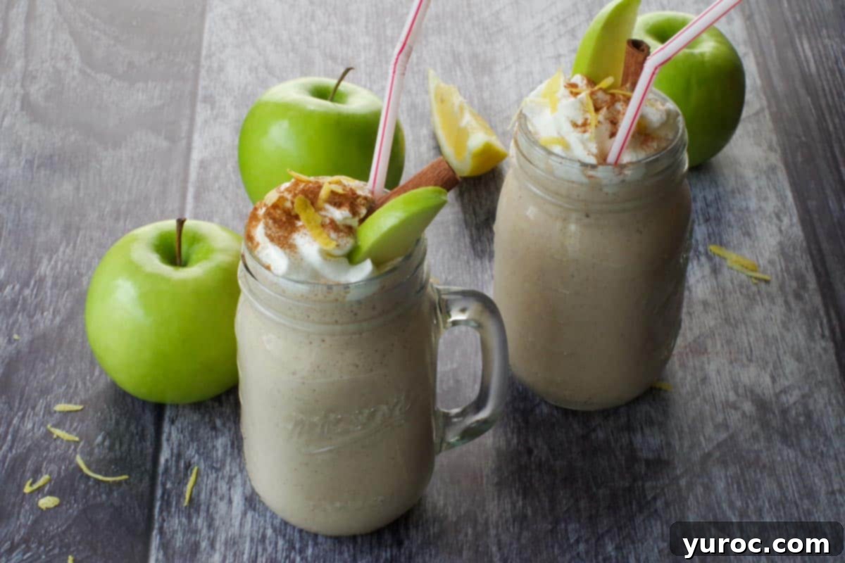 Wholesome Apple Pie Spice Blend 2 Two healthy apple pie smoothies in mason jar mugs with fresh green apples in the background, a perfect fall beverage.