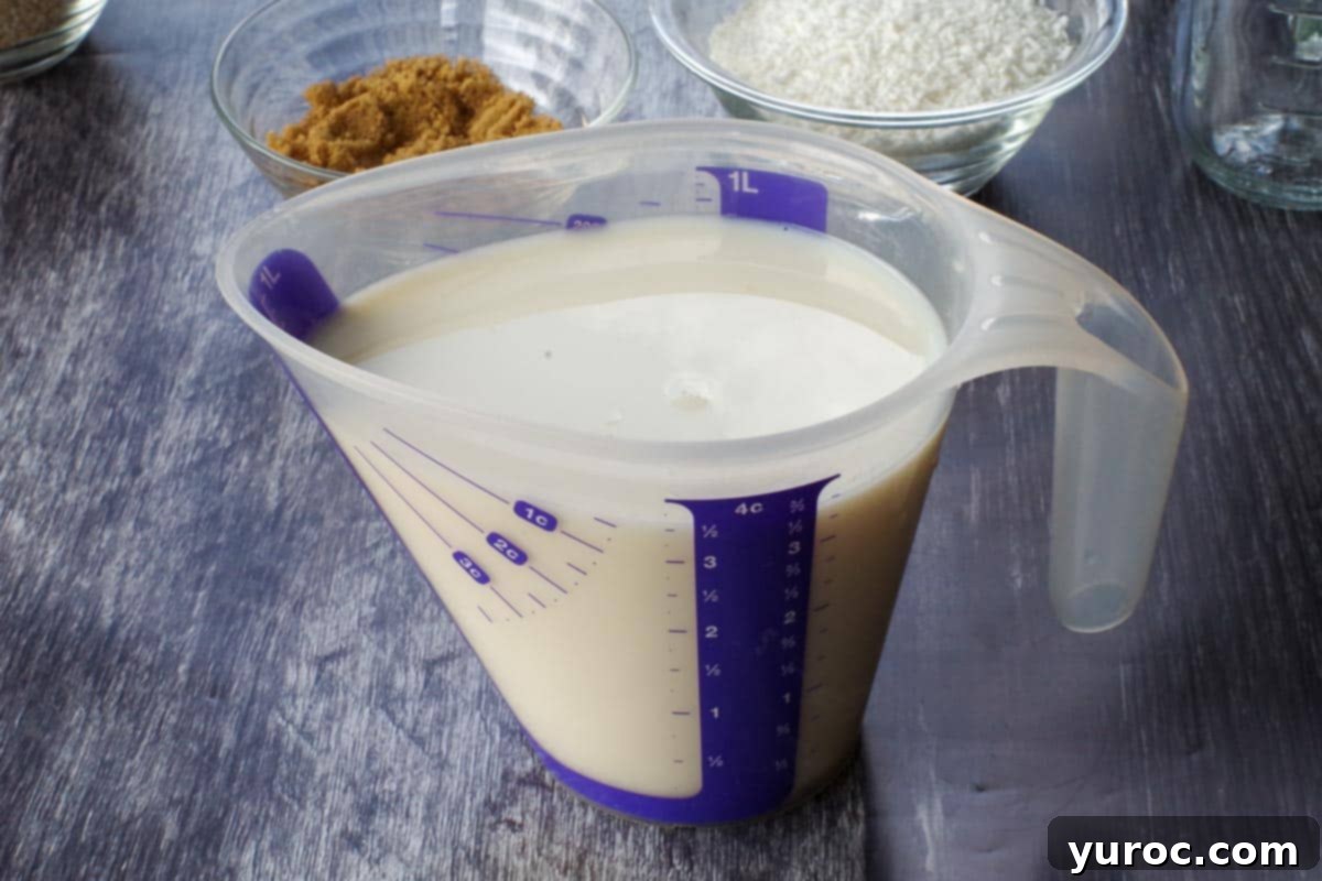 A measuring cup filled with milk, infused with vanilla and orange extract, ready to be poured into the oat mixtures.