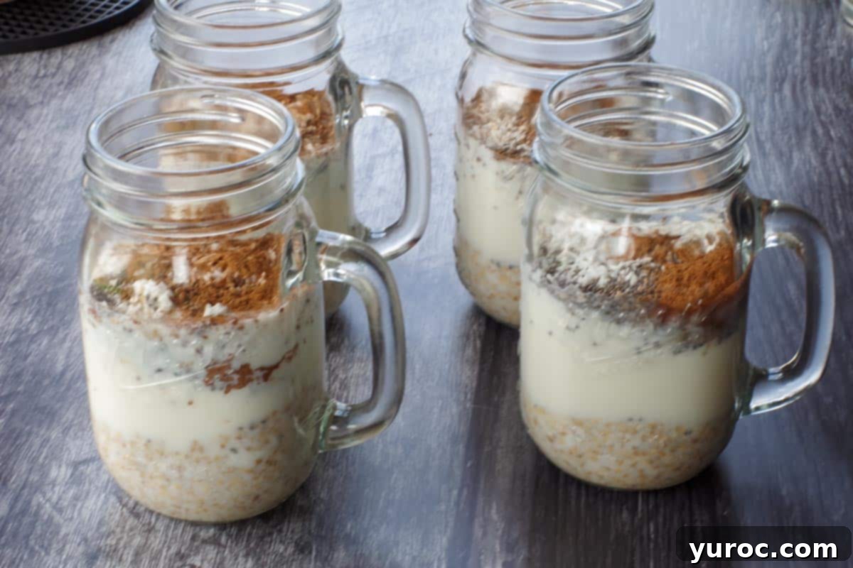 Milk and extract mixture being poured into a mason jar containing the dry overnight oats ingredients.