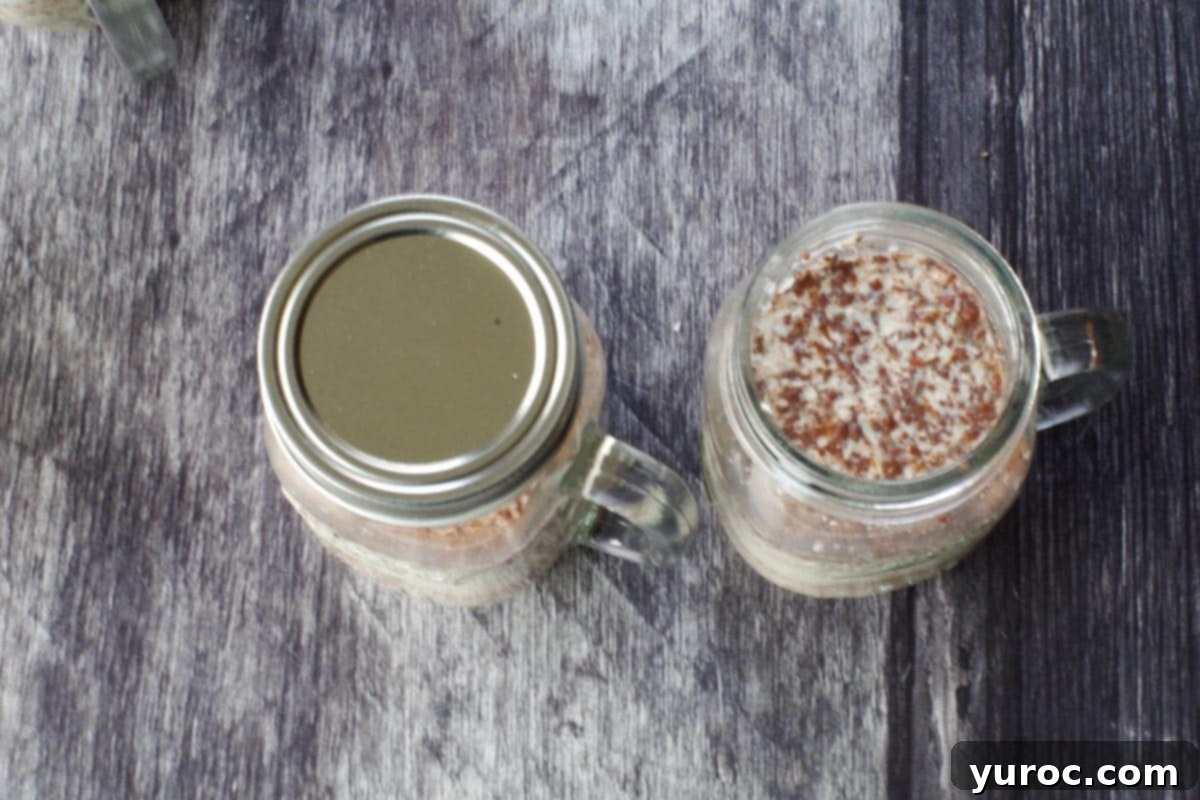 One mason jar of overnight oats is covered with a lid, while another sits uncovered, illustrating the storage method.