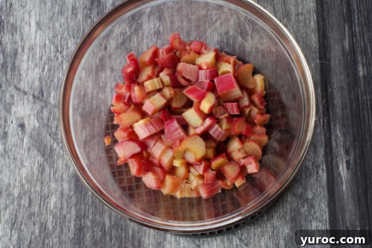 Chunks of rhubarb cooked in a clear glass bowl, softened and ready for the next step of puréeing.