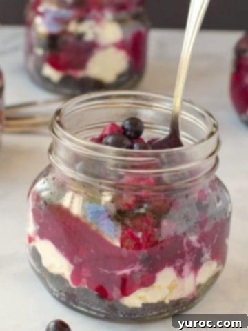 saskatoon berry cheesecake in a jar with a spoon and more jars in the background