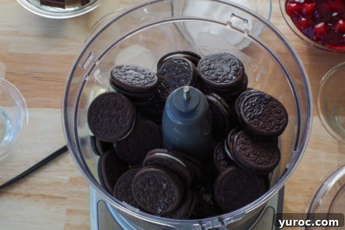 Melted butter combined with Oreo cookies in the bowl of a food processor, ready to be blended for the crust.