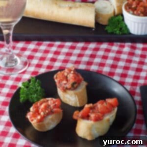 3 pieces of bread with bruschetta on a black plate with a baguette and bruschetta in the background