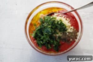 all bruschetta ingredients in a glass mixing bowl with a spoon
