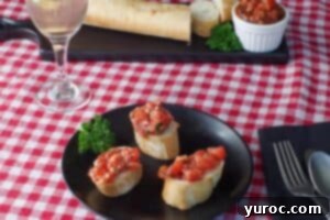 3 pieces of bread with bruschetta on a black plate with a baguette and bruschetta in the background