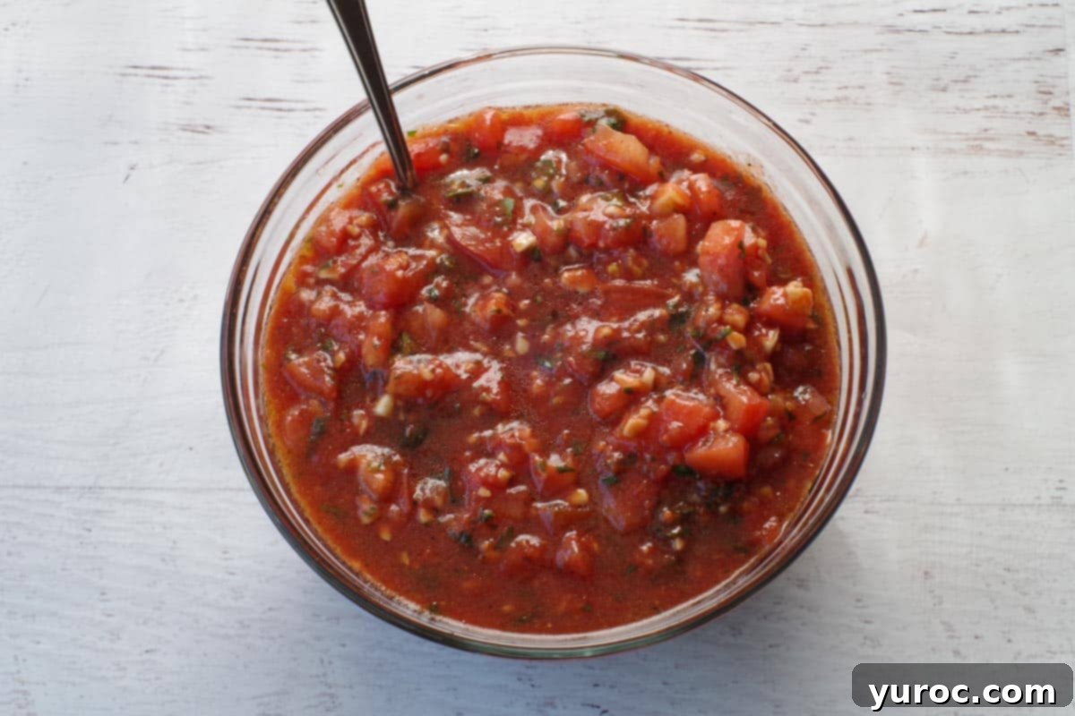 bruschetta ingredients mixed together in glass bowl , with a spoon