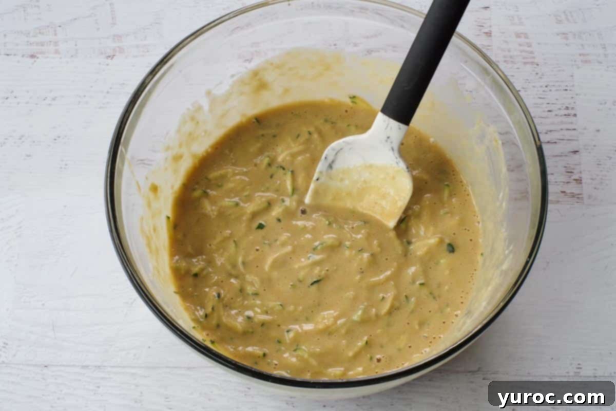 Finely shredded zucchini stirred into the large glass bowl of wet ingredients