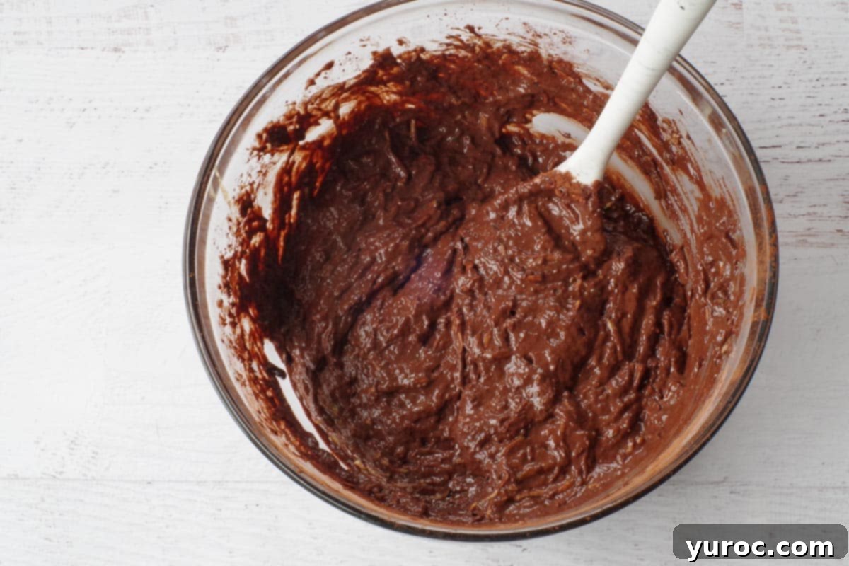 Dry ingredients and wet ingredients gently mixed into a single glass bowl to form batter