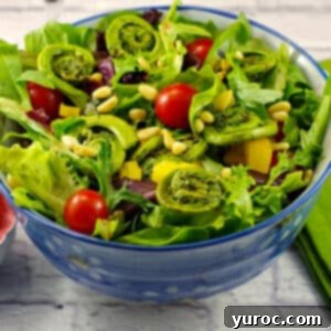Fiddlehead spring salad in a blue bowl on white surface