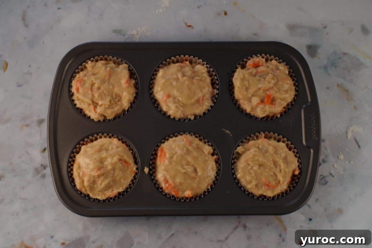 Glazed Carrot Cake Doughnut Muffins 13 Additional muffin batter scooped over the jam filling, filling the muffin cups to the top.