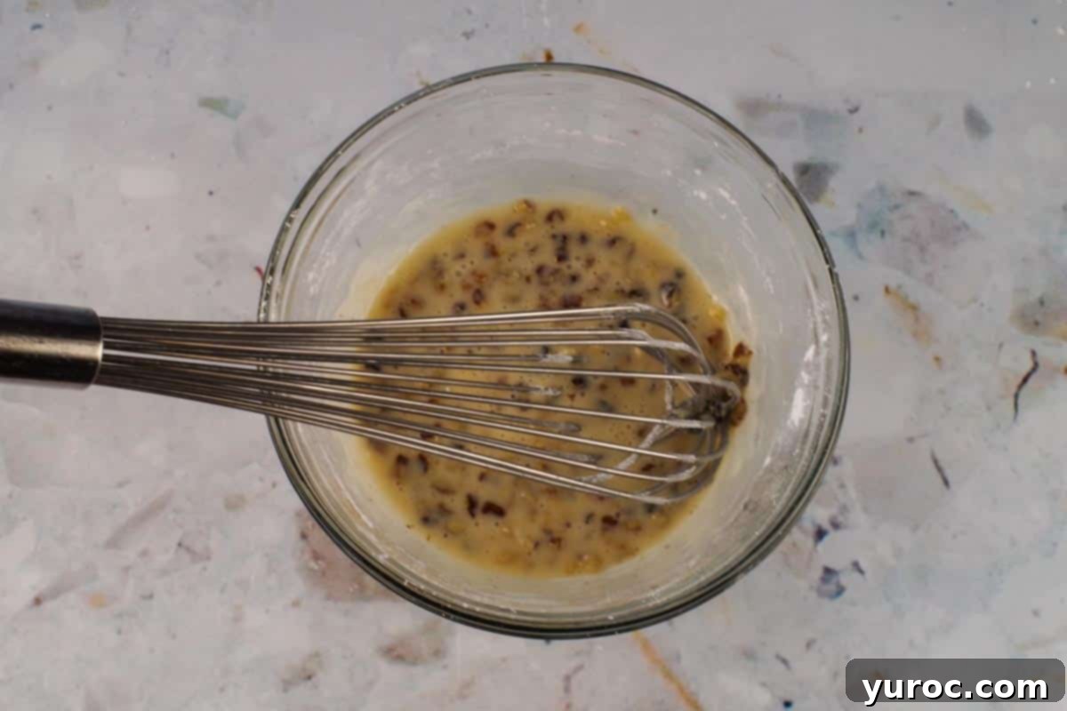 Glazed Carrot Cake Doughnut Muffins 16 Glaze ingredients whisked together in a glass bowl with a metal whisk.